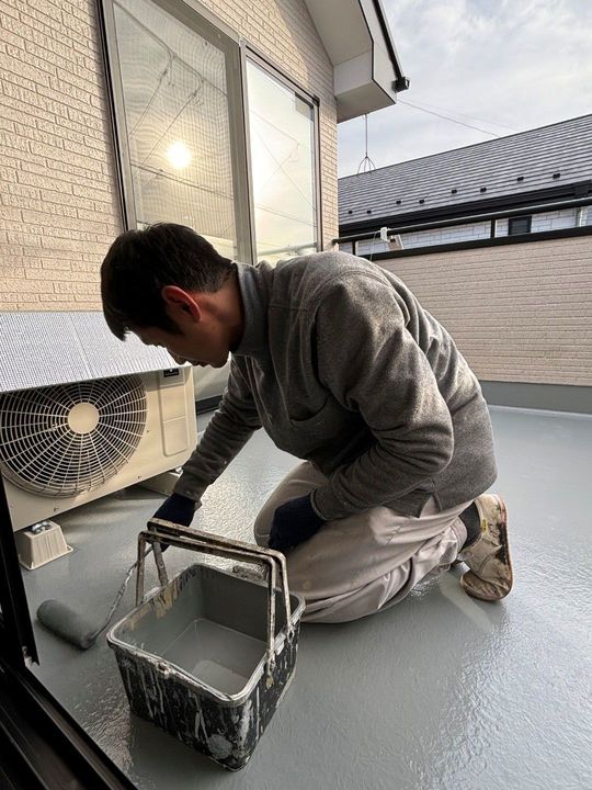 バルコニー防水の上塗りをする職人