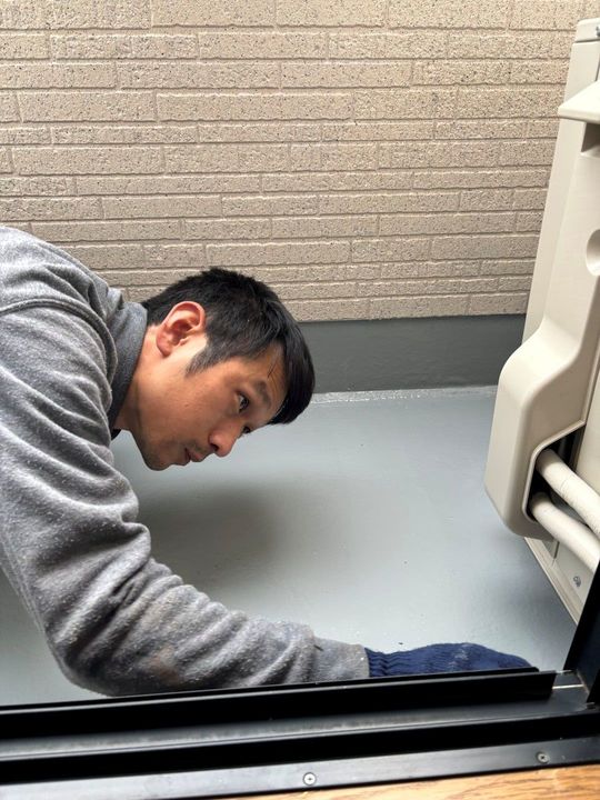 バルコニー防水の上塗りをする職人